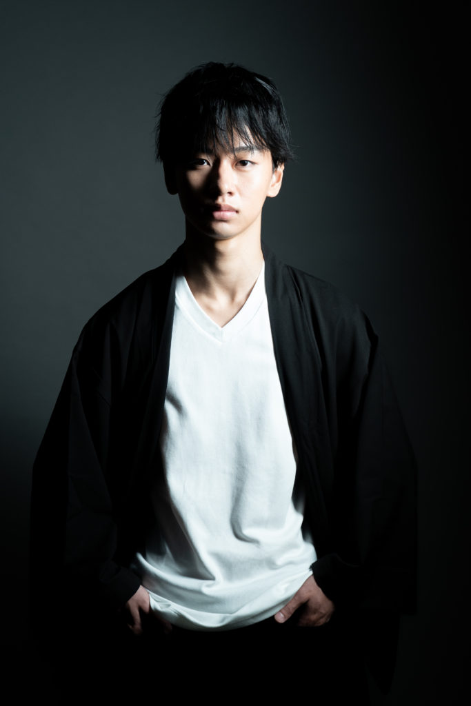 男性がポーズをつけ立っている