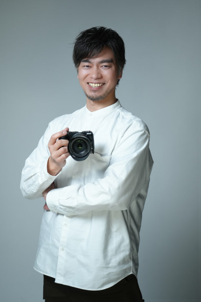カメラを構えて笑顔の男性の写真
