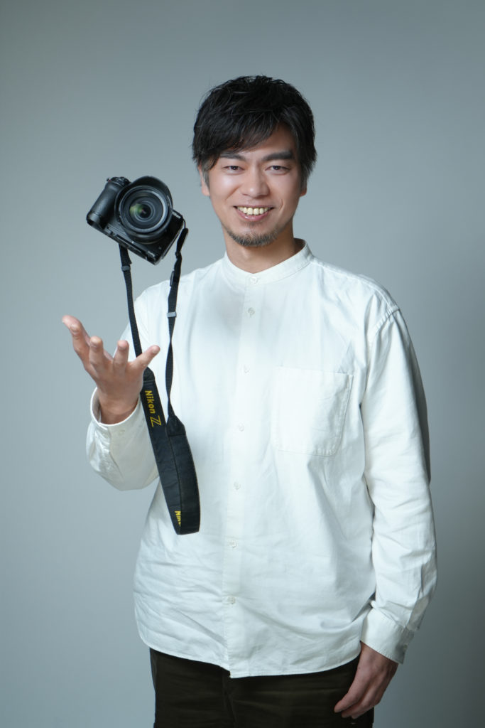 カメラを宙に投げた笑顔の男性の写真