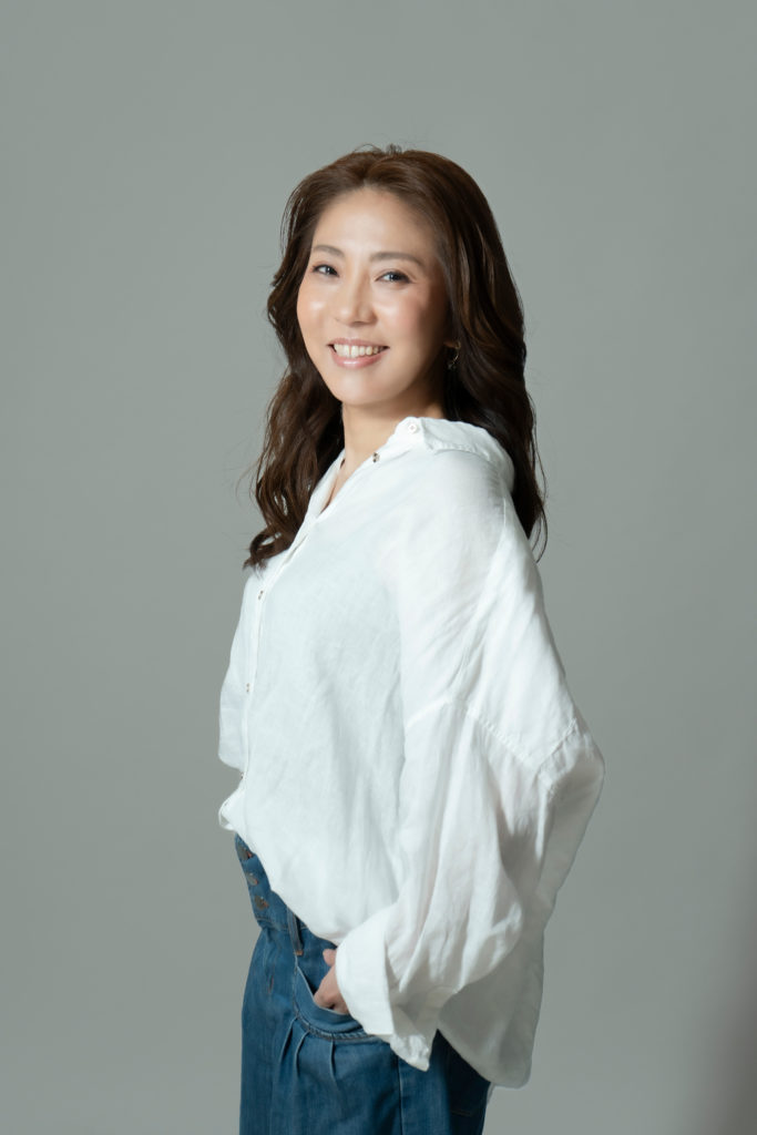 白いシャツを着た女性が笑顔で立っている