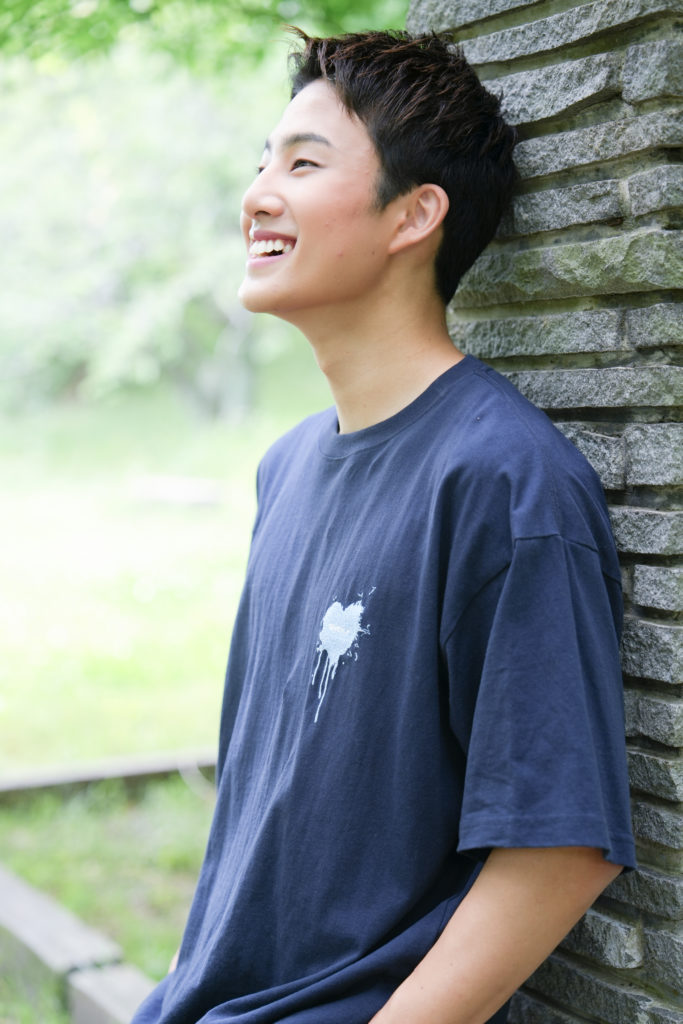 柱に寄りかかり笑顔の男性の写真