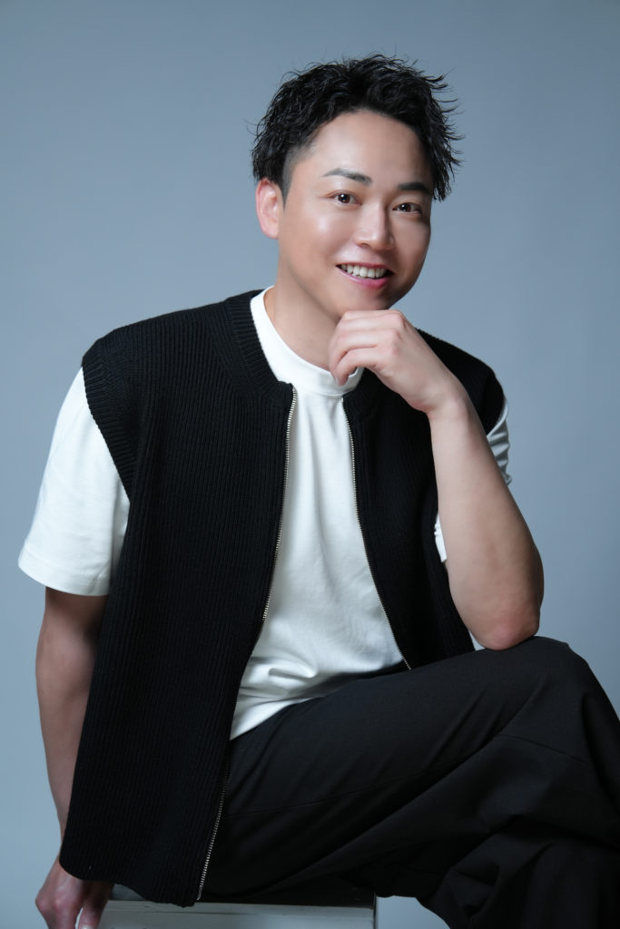 男性がアゴに手を当てて笑顔の写真 