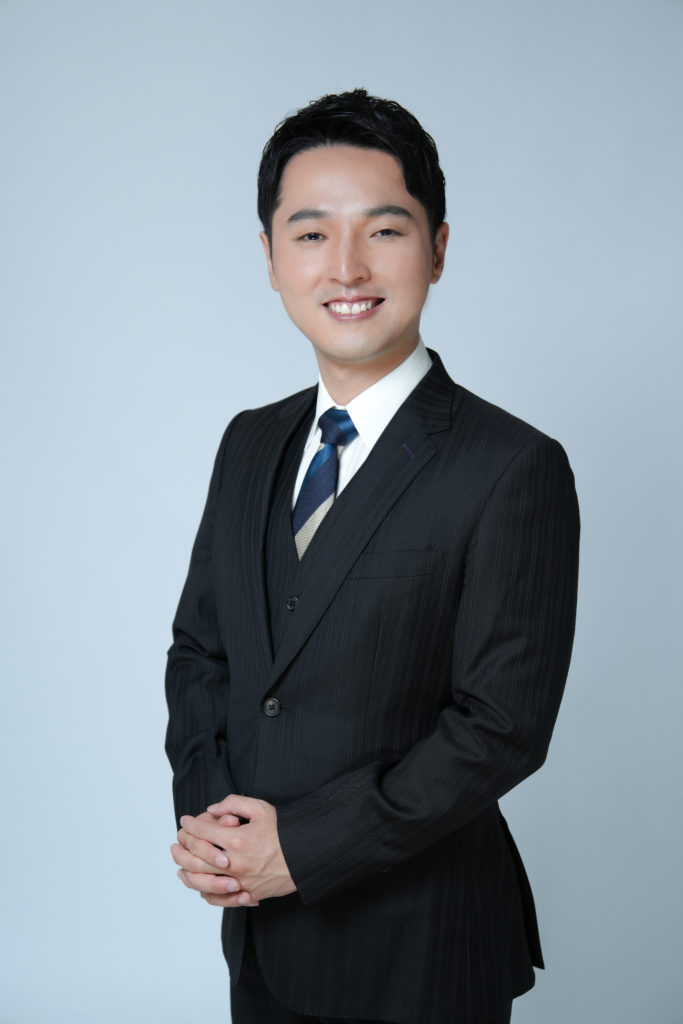 スーツの男性が手を組んで立っている