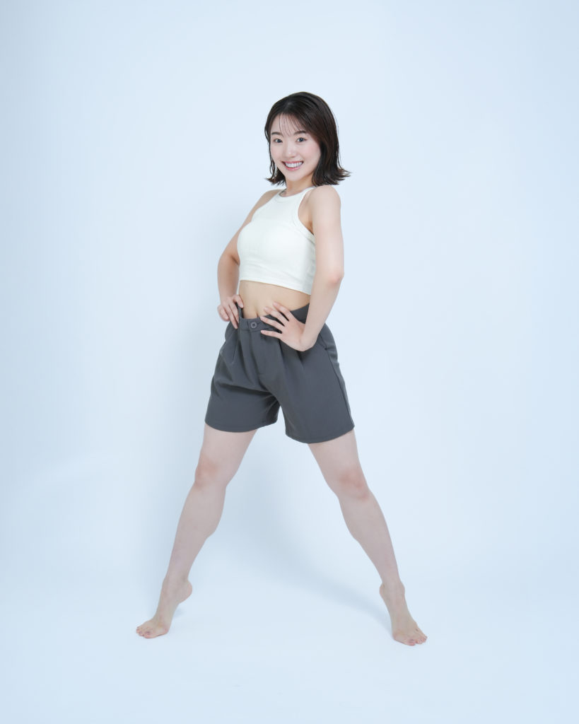 白のタンクトップを着た笑顔の女性の全身の写真