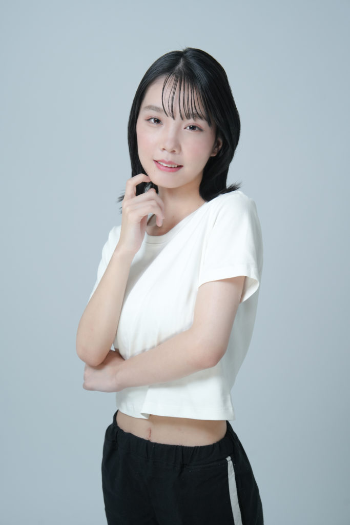 白いTシャツを着た女性が顎に手をかけている写真