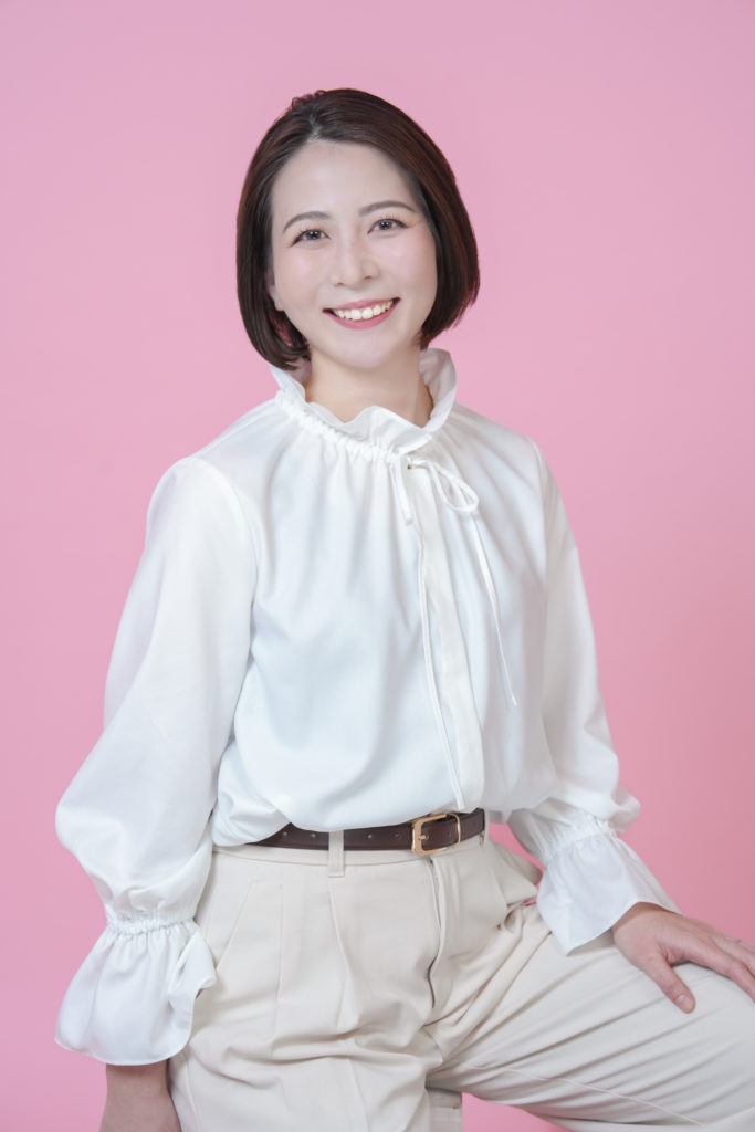 Studio Fictionで撮影した、ピンク色の背景で白色ブラウスを着た女性のポートレート写真